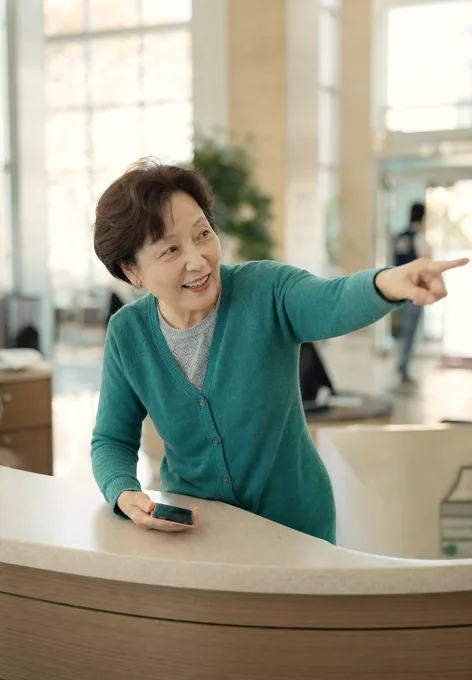 A hospital volunteer smiling as she points a visitor the right way across the lobby